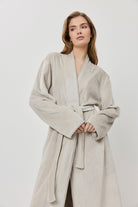 Woman wearing a beige robe against a white background