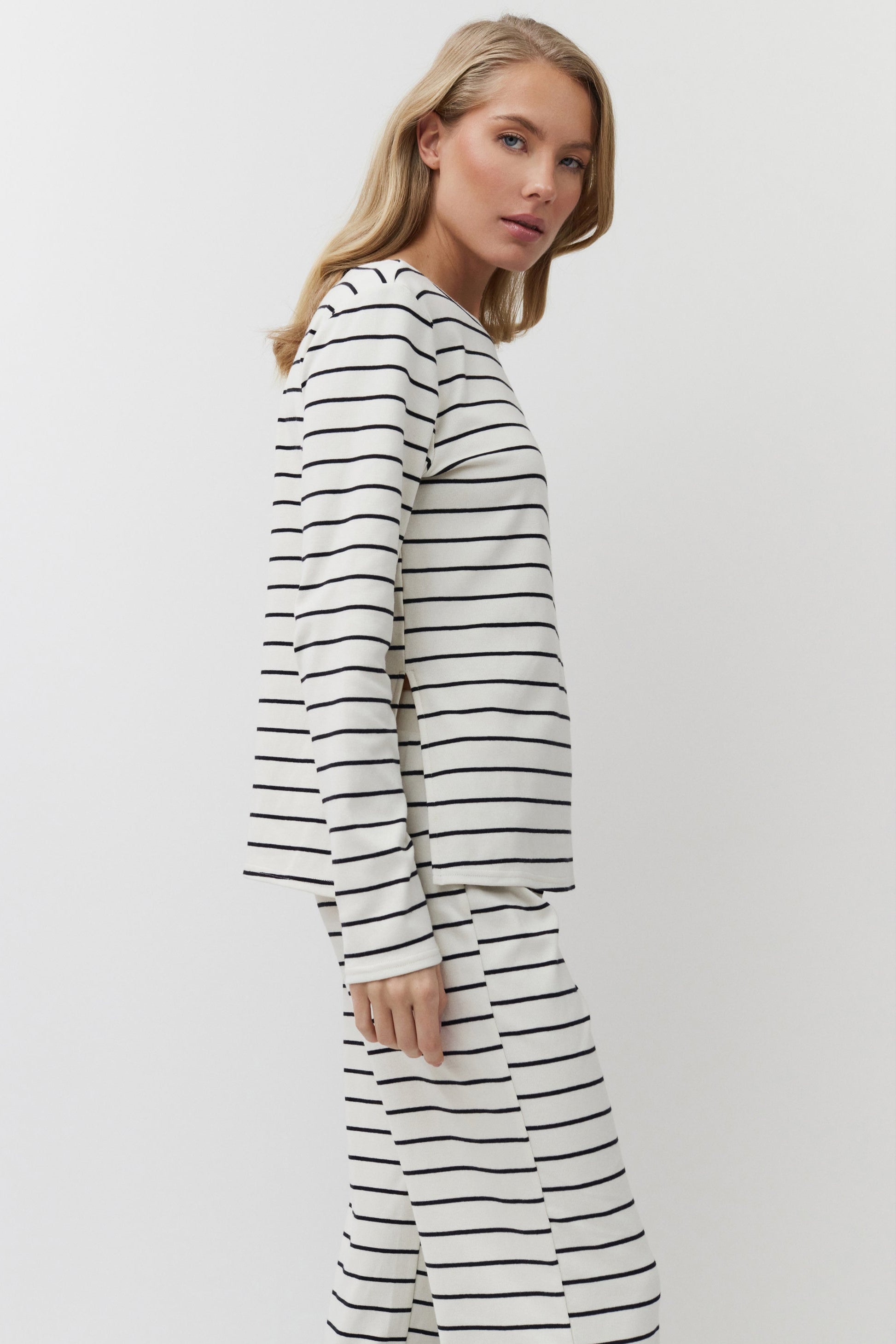 Woman wearing a long-sleeve, black and white striped set against a plain background