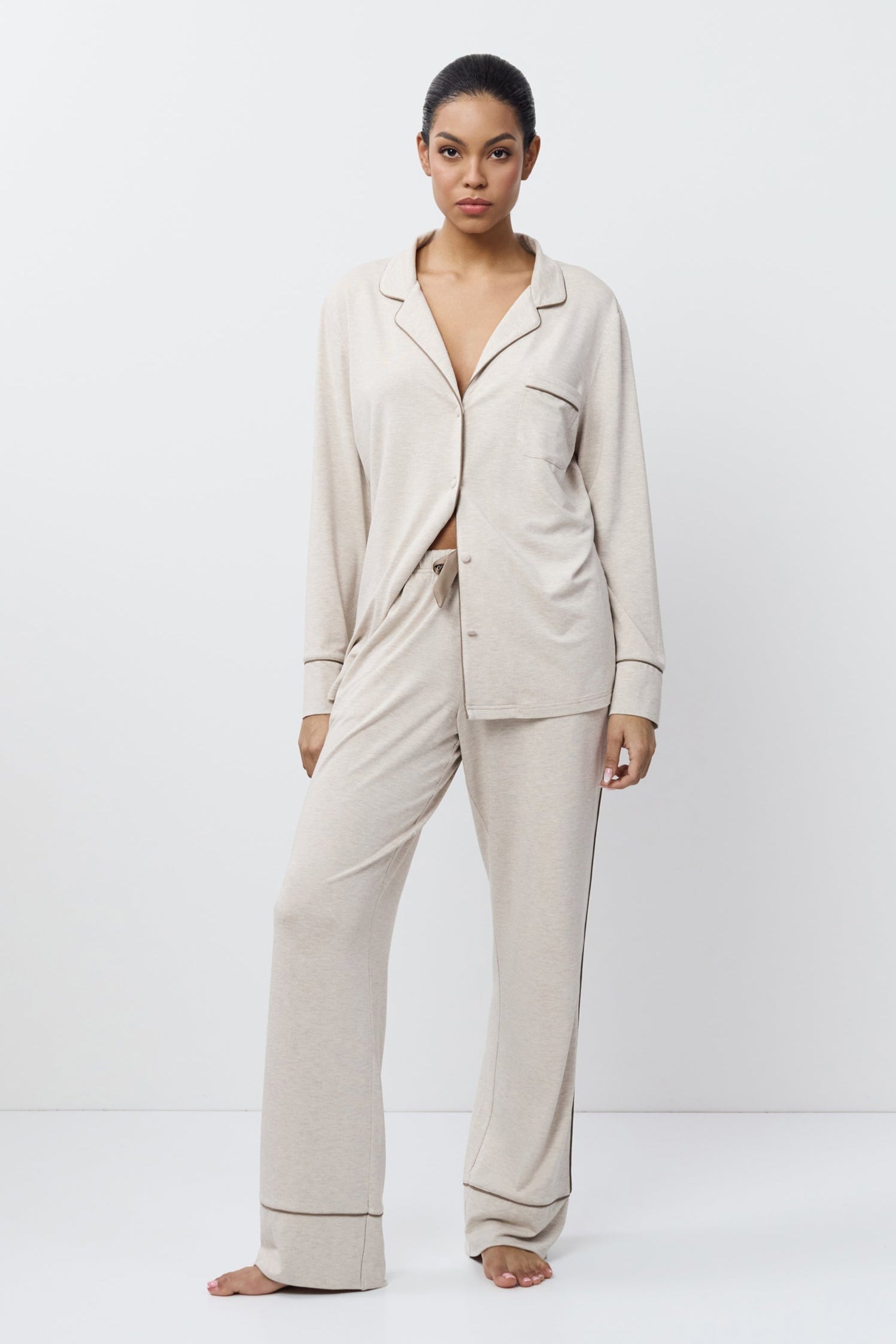 Woman wearing a beige pajama set on a white background