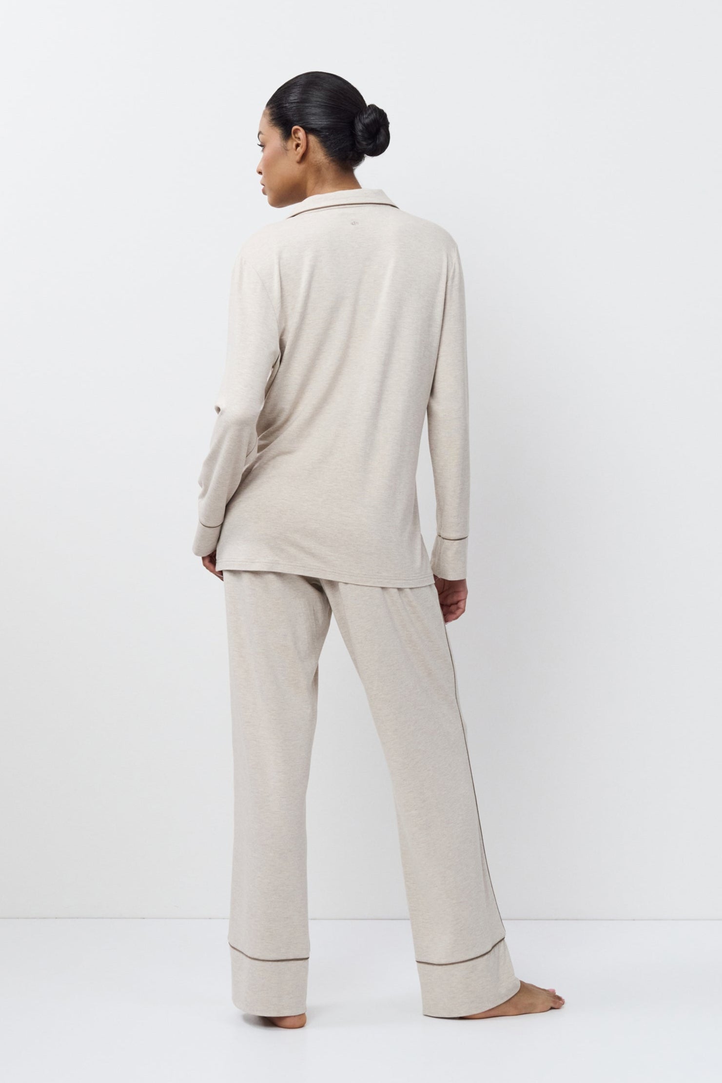 Person wearing a beige set standing against a white background