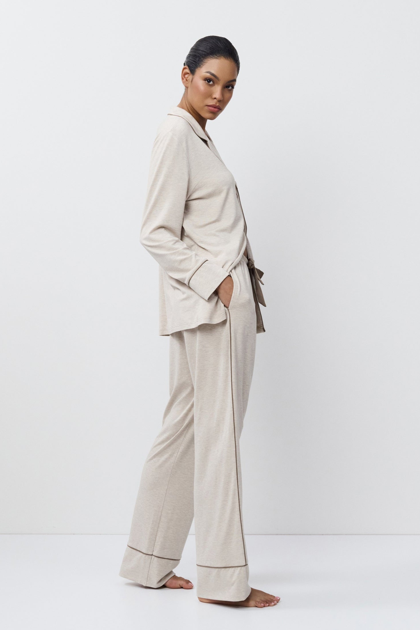 Woman wearing a beige set standing against a white background