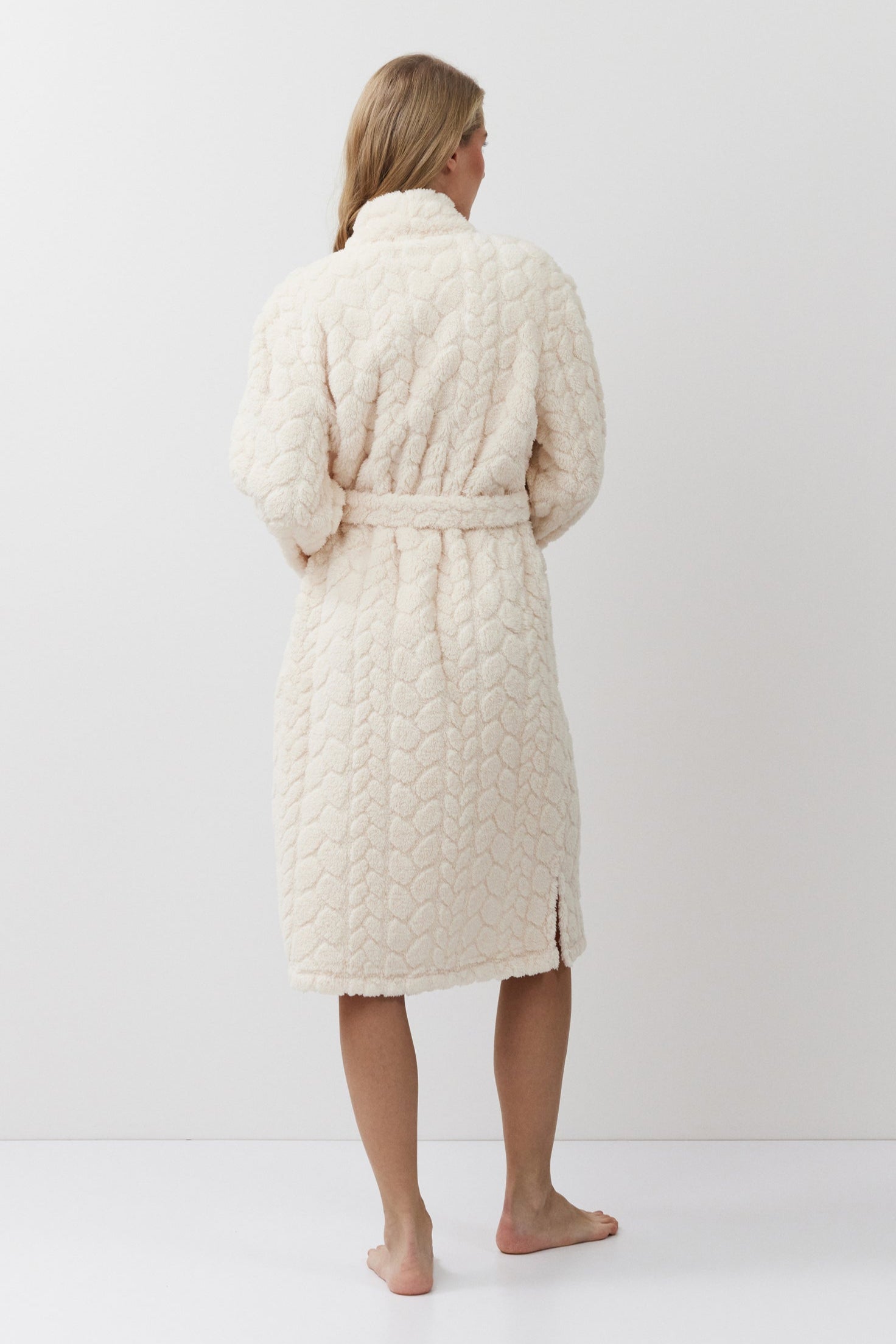 Woman wearing a cream quilted bathrobe against a white background