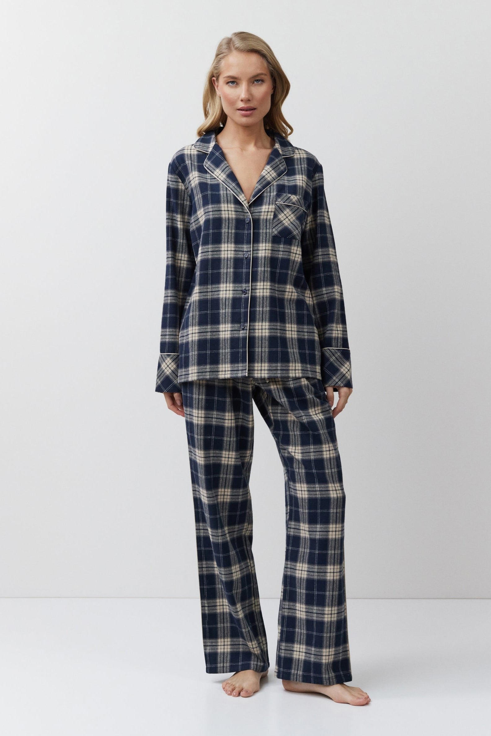 Woman wearing a navy and beige plaid pajama set on a white background