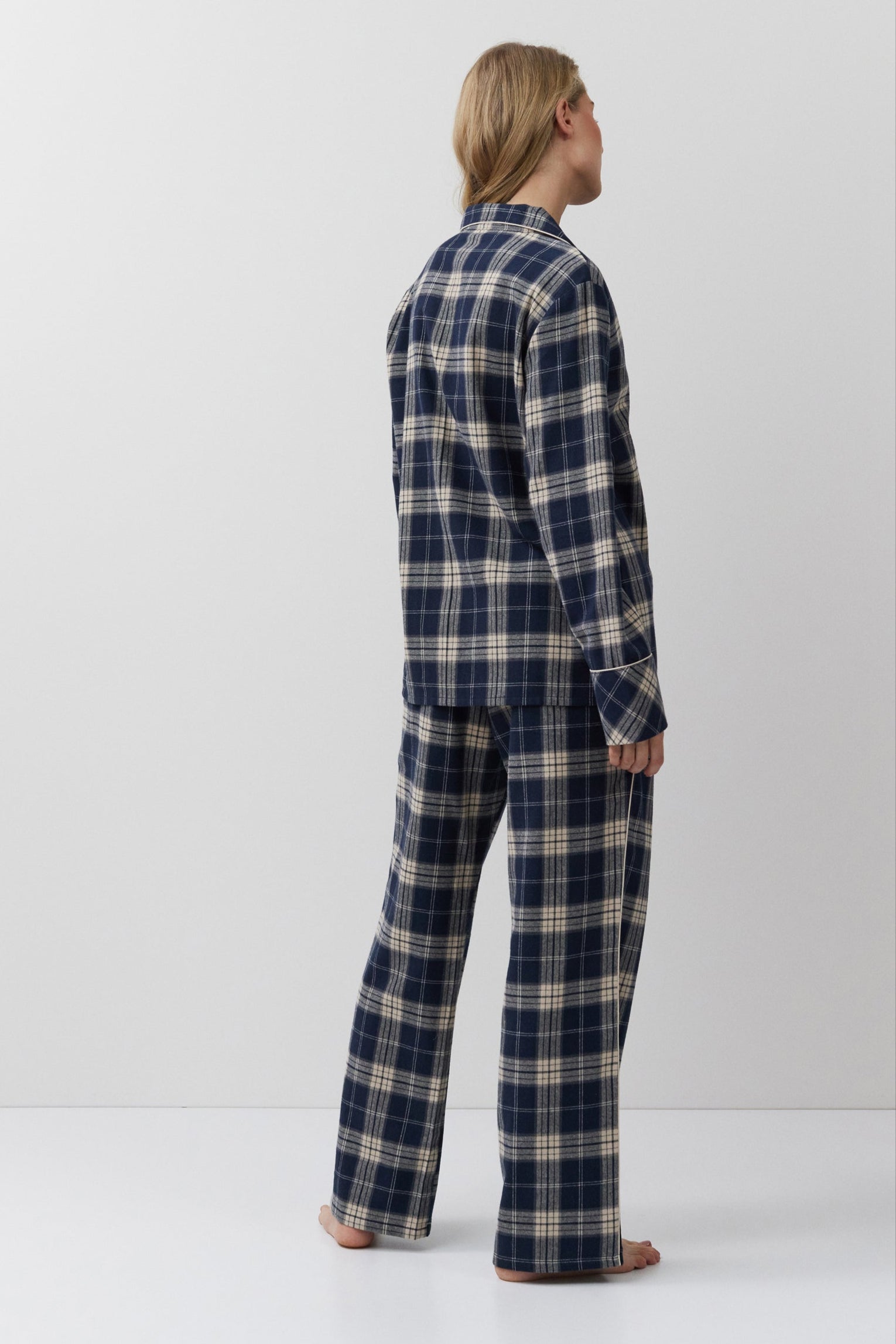 Person wearing a blue and beige plaid pajama set against a white background