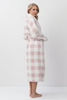 Woman wearing a pink and white checkered bathrobe on a white background