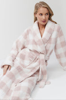 Woman wearing a pink and white checkered robe on a white background