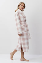 Woman wearing a pink and white checkered bathrobe on a white background