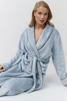 Woman wearing a light blue bathrobe against a white background