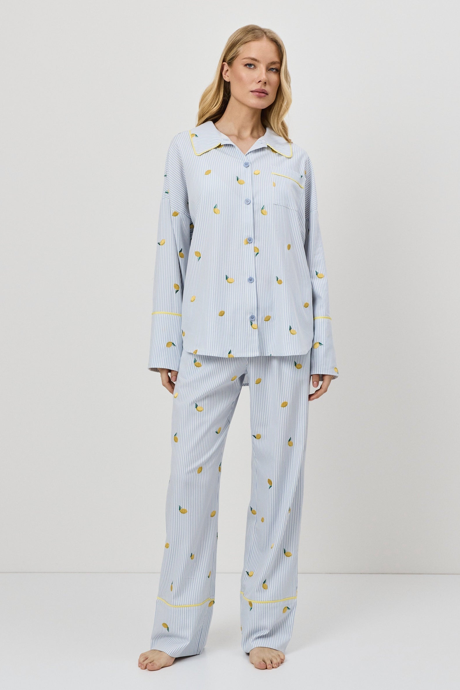 Woman wearing light blue pajamas with a lemon embroideries on a white background