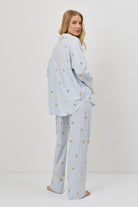 Woman wearing a light blue pajama set with a lemon emroyderies on a white background
