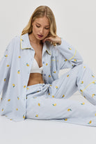 Woman wearing a light blue pajama set with lemon pattern on a white background