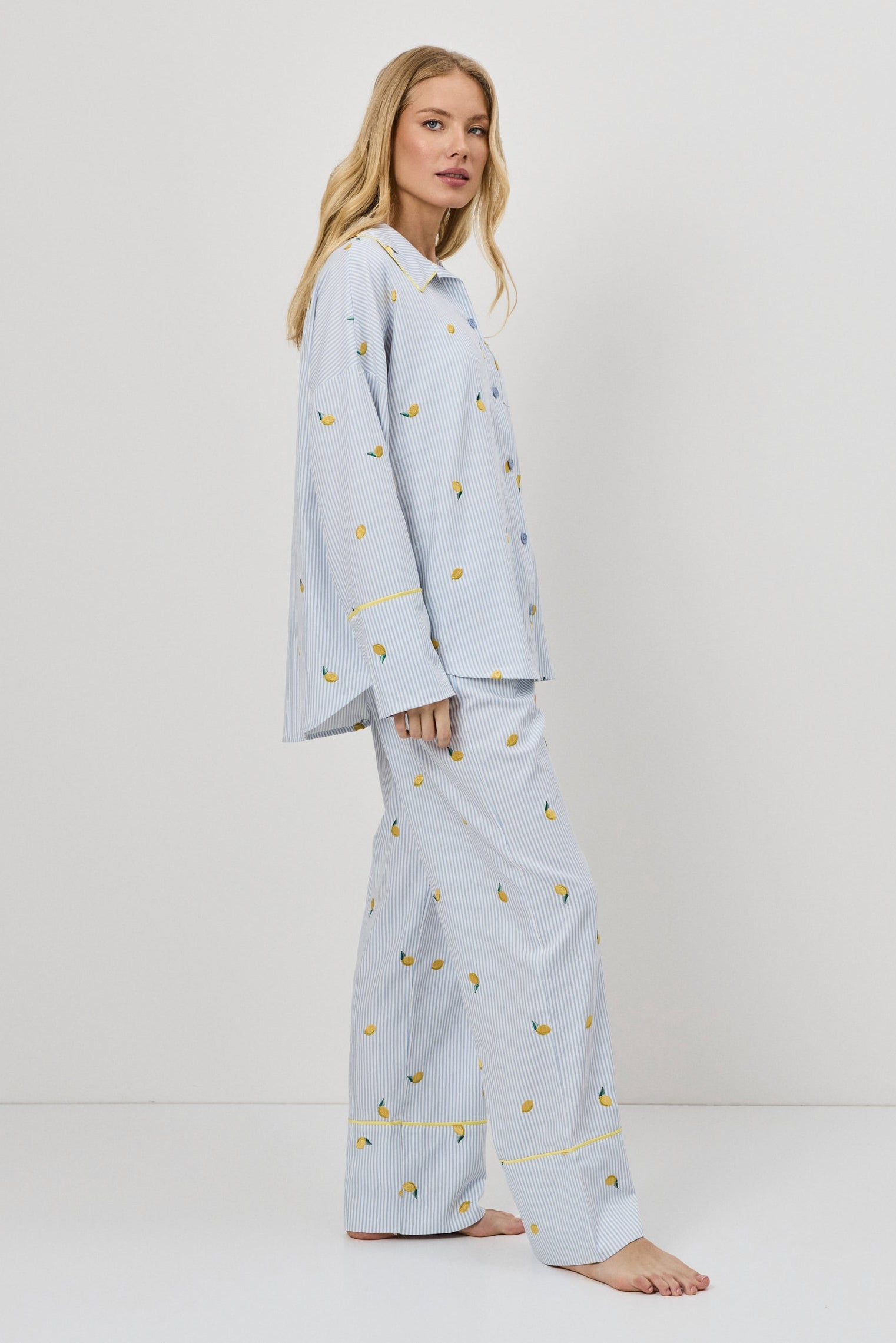 Woman wearing light blue pajamas with a lemon embroideries on a white background