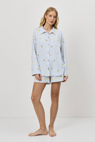 Woman wearing a light blue pajama set with a lemon embroideries on a white background