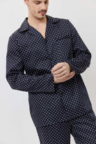 Man wearing a navy blue pajama set with white star pattern on a light gray background