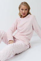 Woman wearing pink set sitting on a white surface