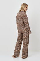 Woman wearing a leopard print pajama set on a white background