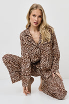 Woman wearing a leopard print pajama set on a white background