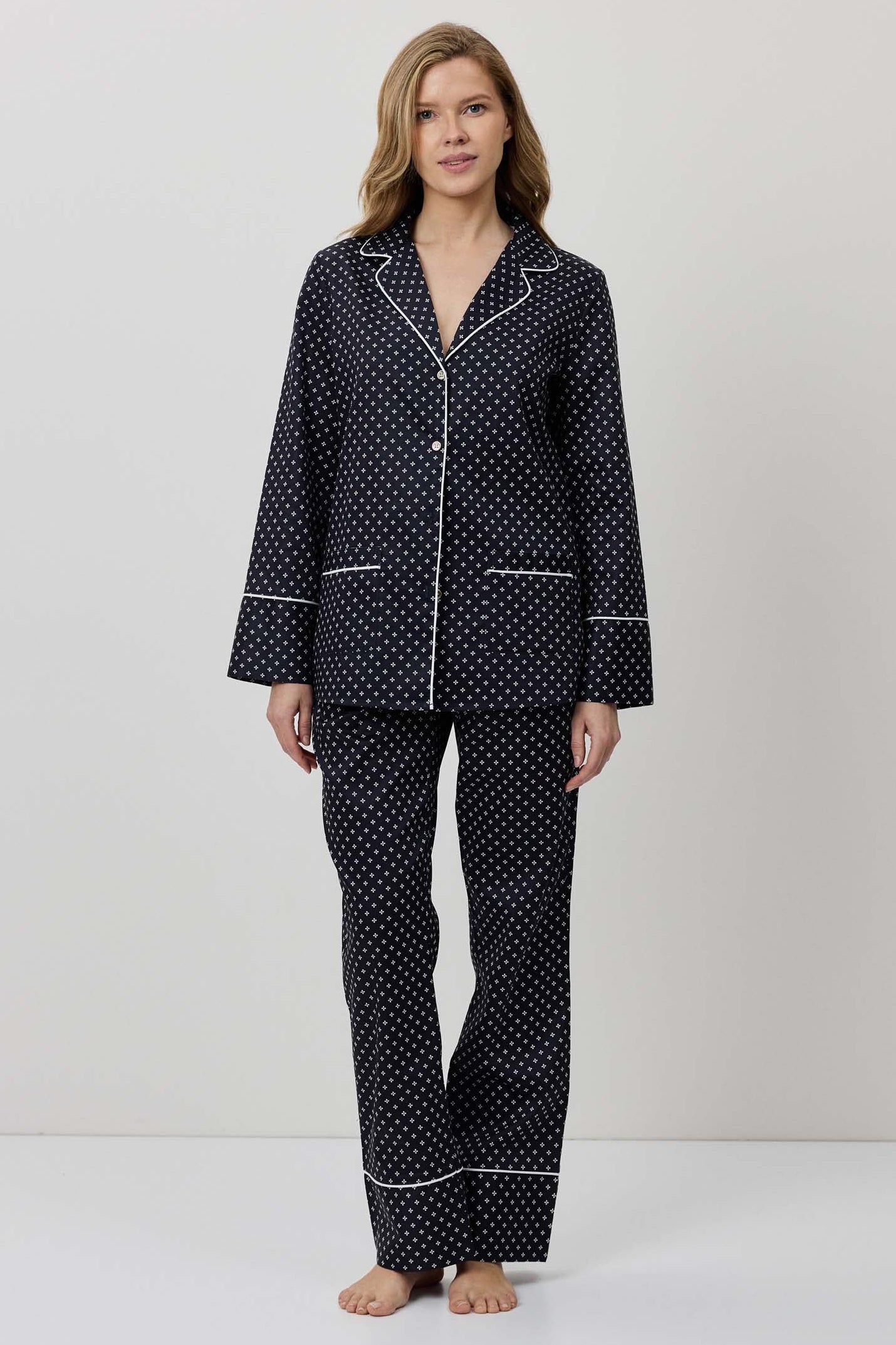 Woman wearing a black polka dot pajama set on a white background