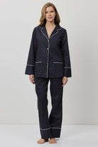 Woman wearing a black polka dot pajama set on a white background