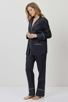 Woman wearing a navy polka dot pajama set on a white background