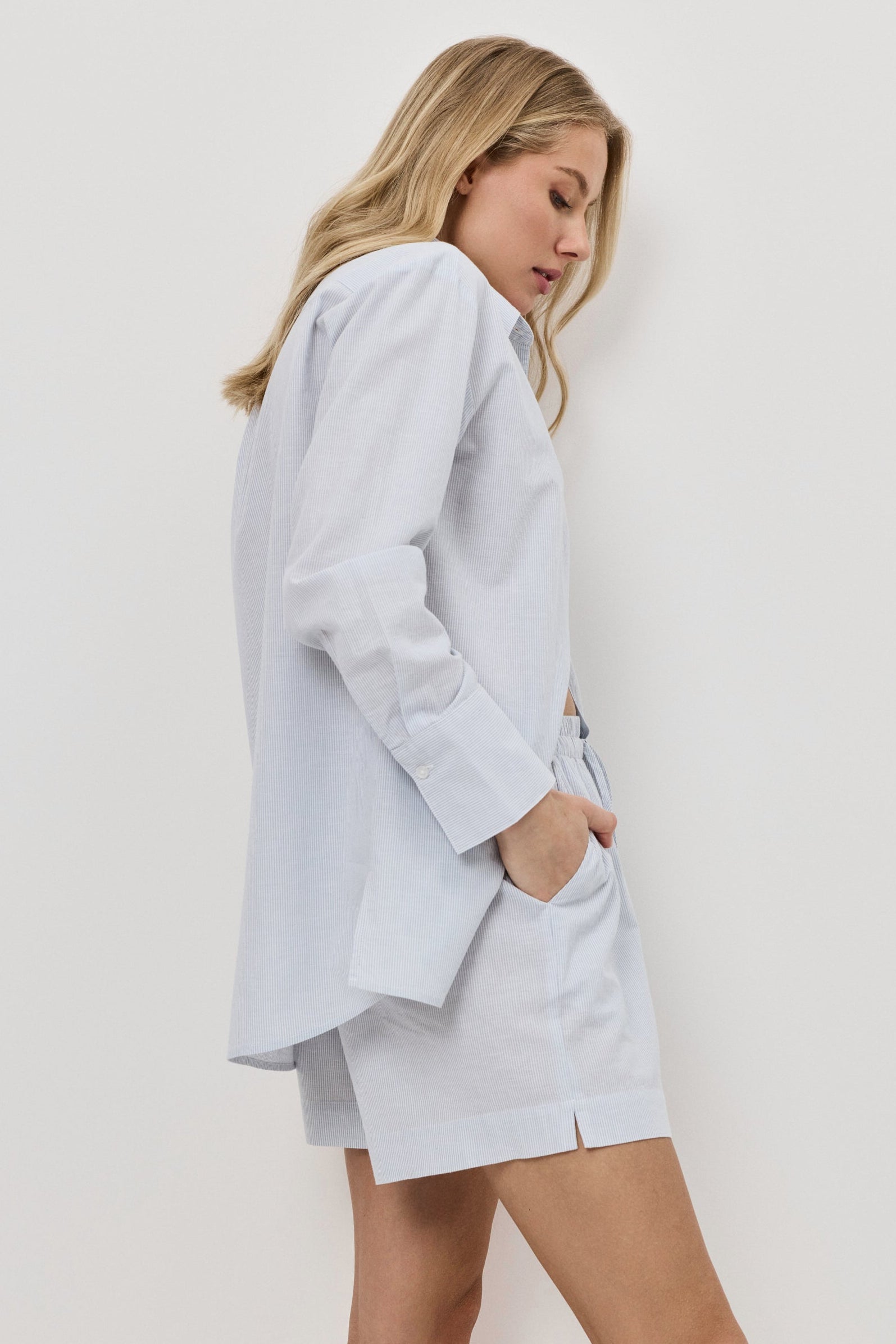 Woman wearing a light blue resort wear set  against a white background
