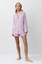 Woman wearing a lilac pajama set on a white background