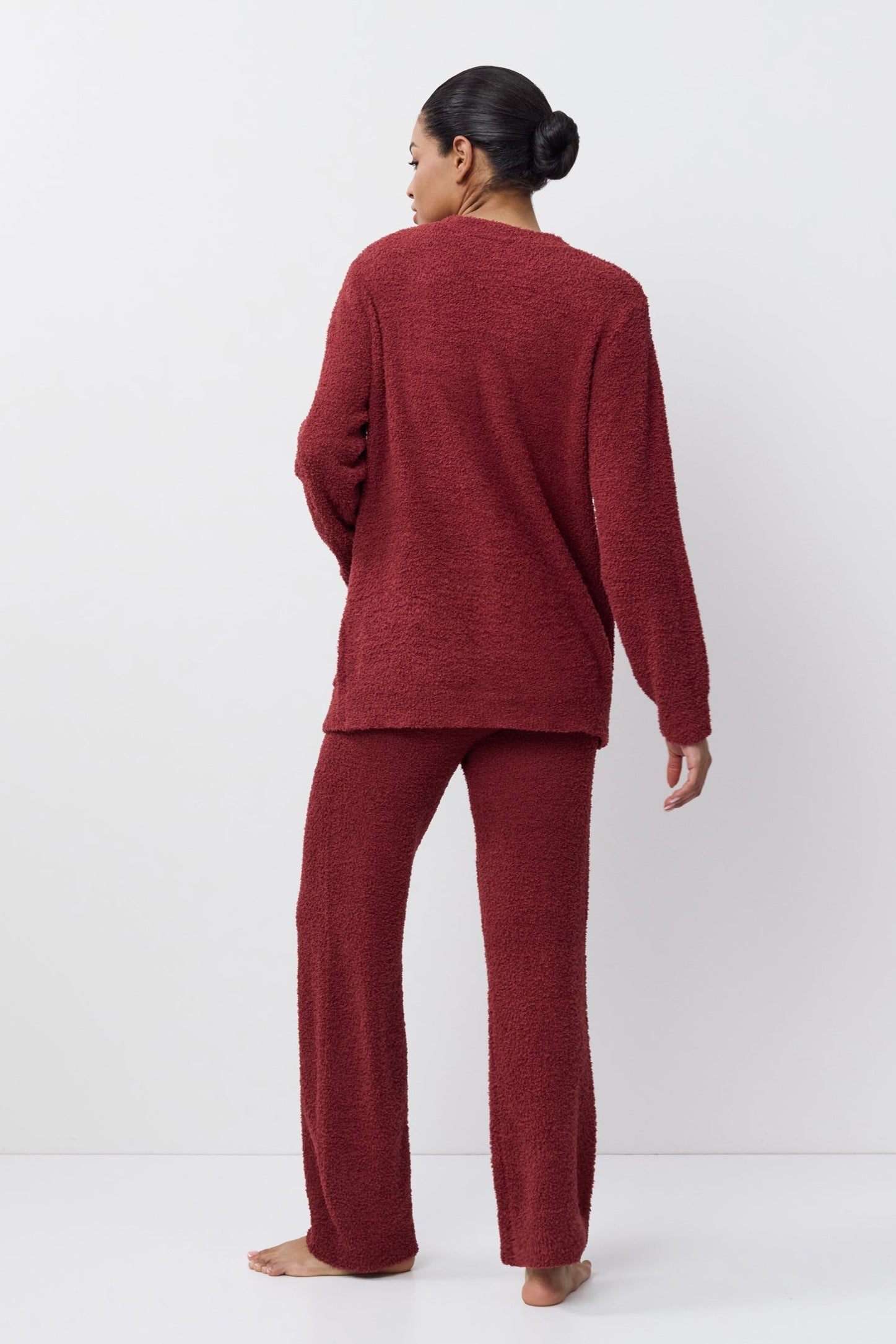 Person wearing a burgundy lounge set on a white background