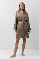 Woman wearing a brown satin gown against a white background