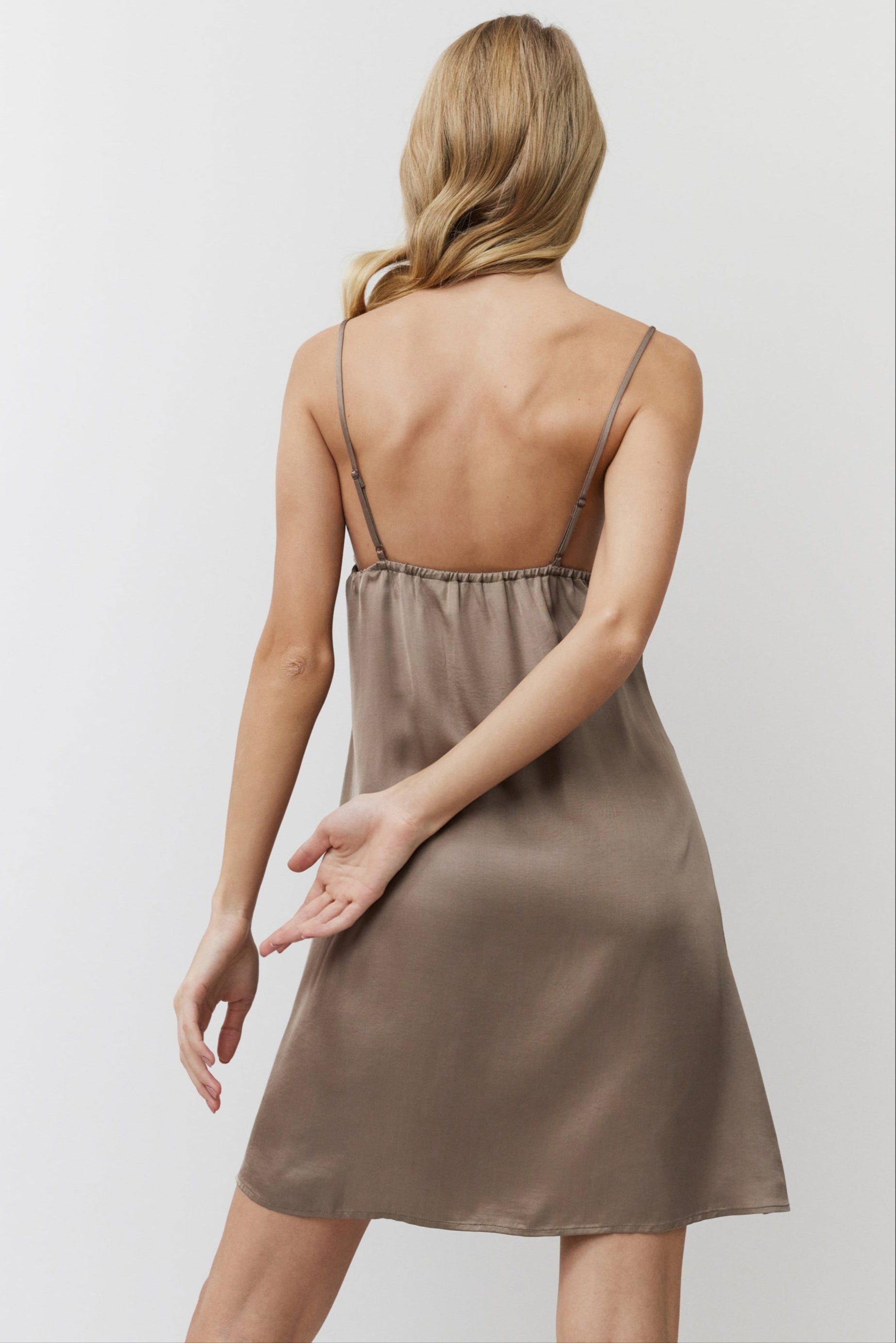 Woman wearing a brown satin nightdress against a plain background