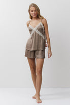 Woman wearing a brown pajama set with lace details on a white background