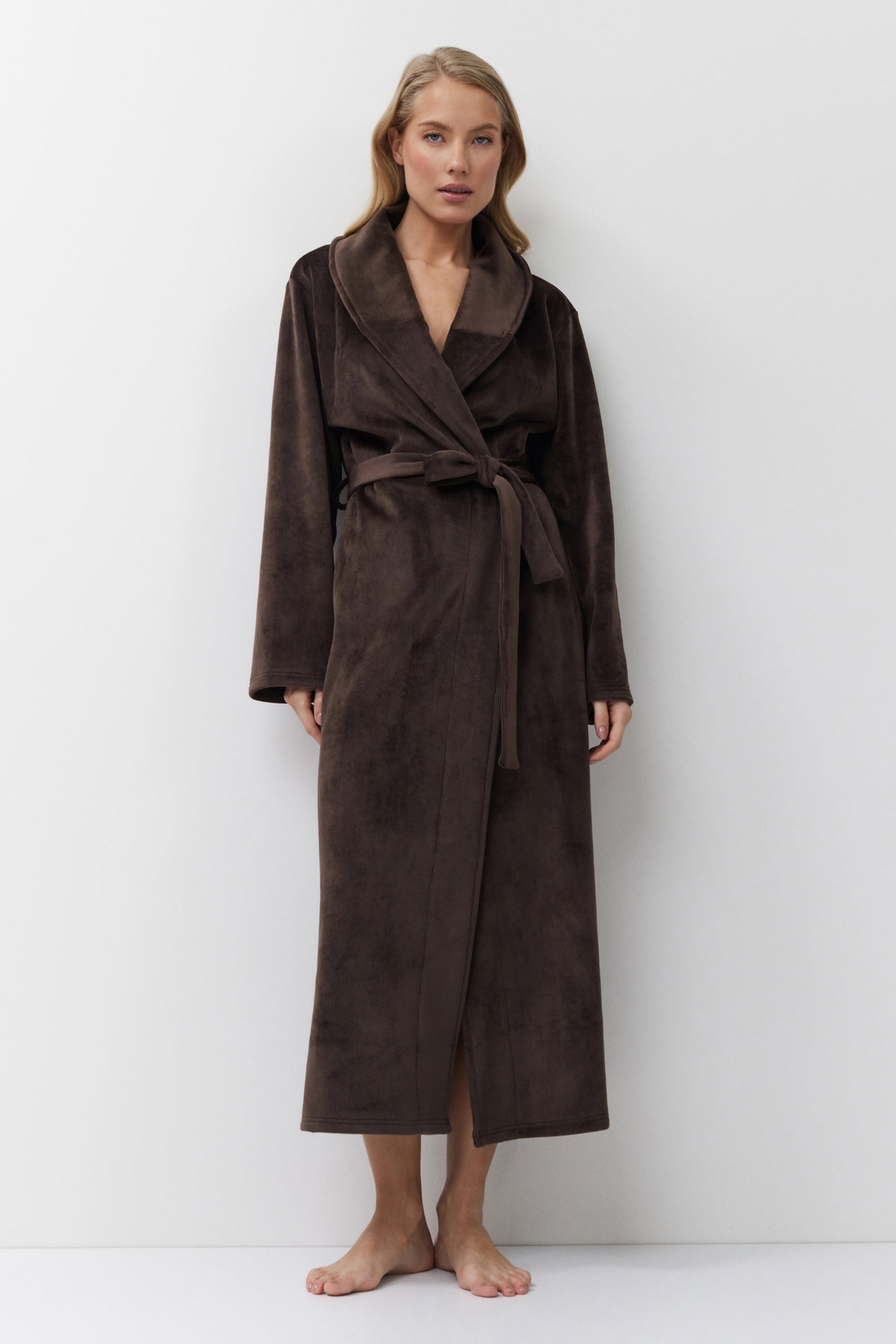 Woman wearing a brown bathrobe against a white background
