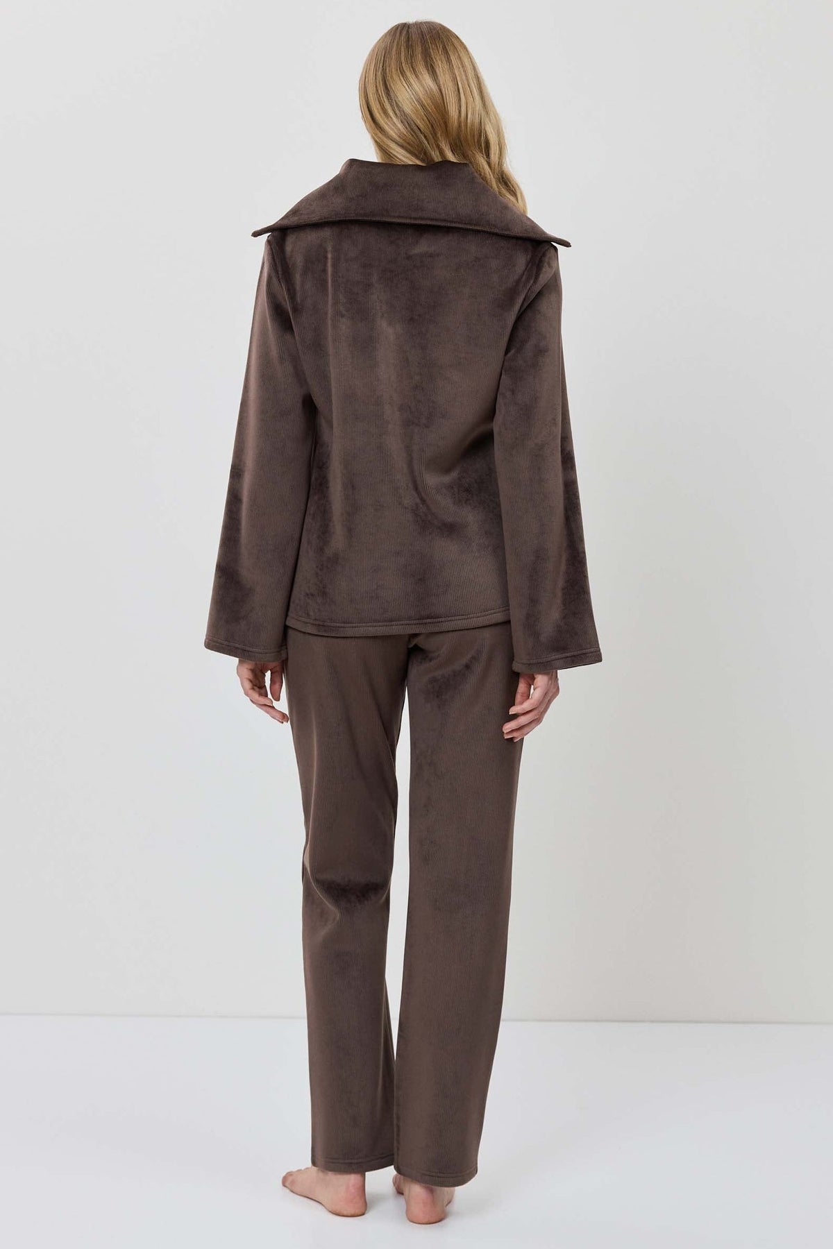 A woman modeling a matching two-piece lounge set in dark brown, featuring a long-sleeve half-zip pullover and coordinating pants.