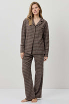 Woman wearing a brown checkered pajama set on a white background