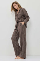 Woman wearing a brown checkered pajama set against a white background