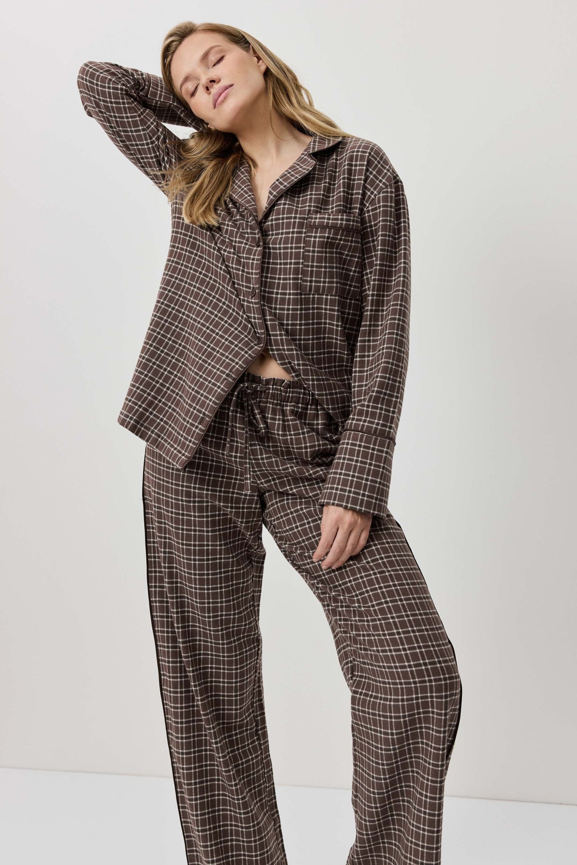 Woman wearing a brown plaid suit against a white background