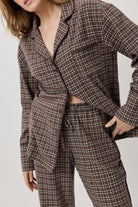 Person wearing a brown plaid suit against a plain background