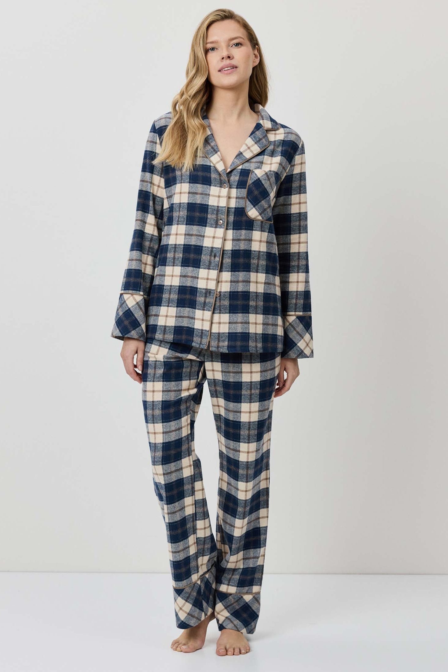 Woman wearing a blue and beige plaid pajama set on a white background