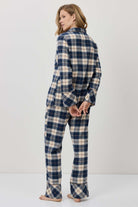 Woman wearing a blue and white plaid pajama set against a plain background