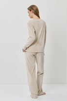 Woman wearing a beige long-sleeve top and pants on a white background