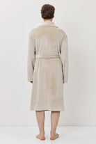 Person wearing a beige robe standing against a white background