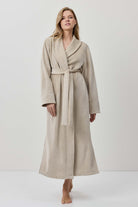 Woman wearing a beige robe against a white background
