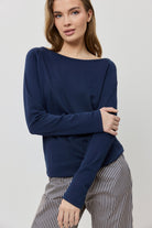 Woman wearing a navy blue sweater and striped pants on a light gray background