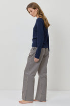 Woman wearing a navy sweater and gray checkered pants on a white background