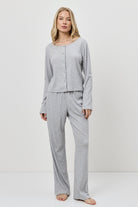 Woman wearing a gray pajama set against a white background