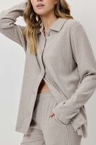 Person wearing a light gray ribbed knit suit on a white background