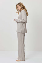 Woman wearing a gray suit standing against a white background