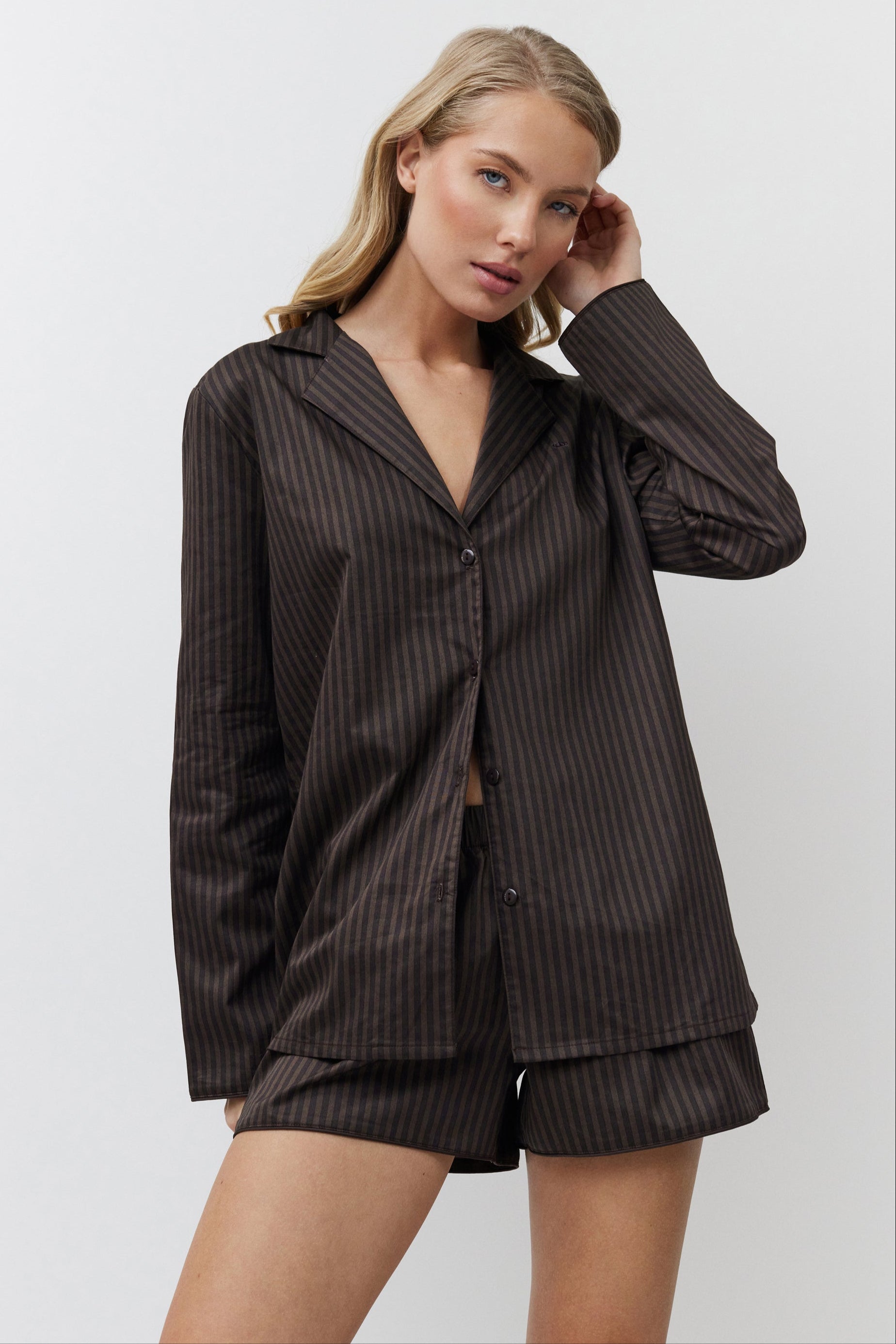 Woman wearing a brown pajama set against a white background