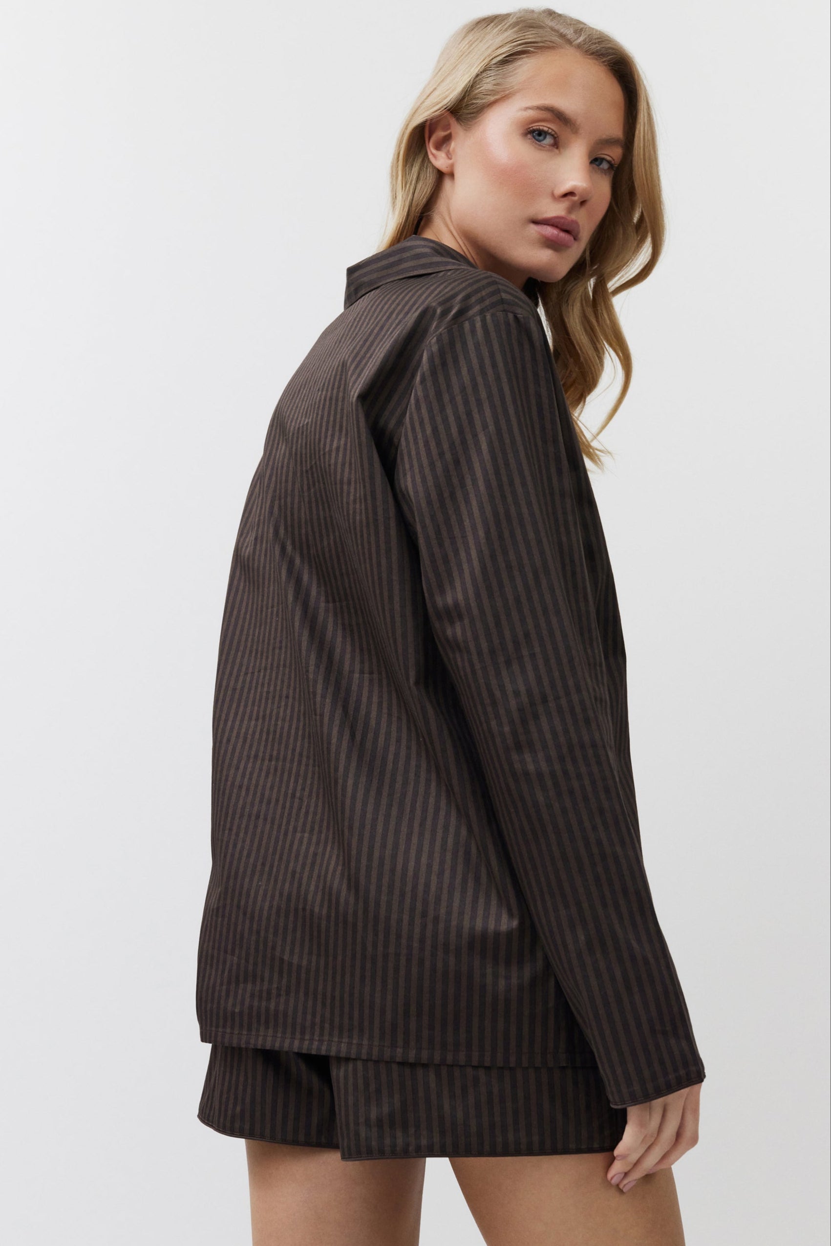 Woman wearing a brown pajama set with shorts on a white background