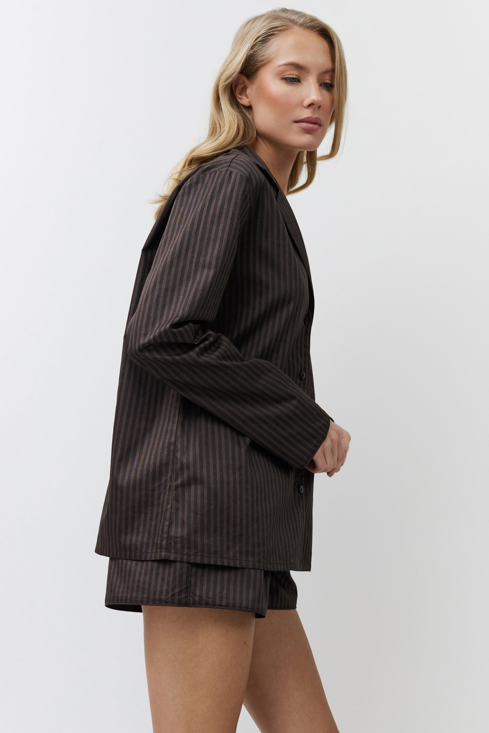 Woman wearing a brown pajama set on a white background