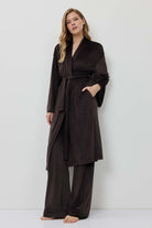 Woman wearing a dark brown robe against a white background